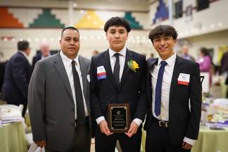 Two alumni students posing with their dad at the Annual Celebration