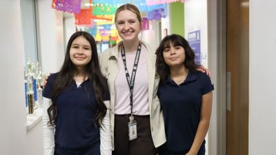 2 ucc acosta female students smiling with teacher in the hallway