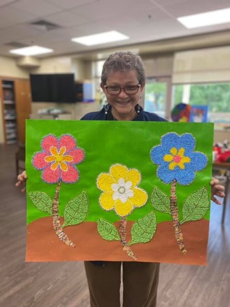 Photo of UCC Adult Day Center female client holding a piece of art
